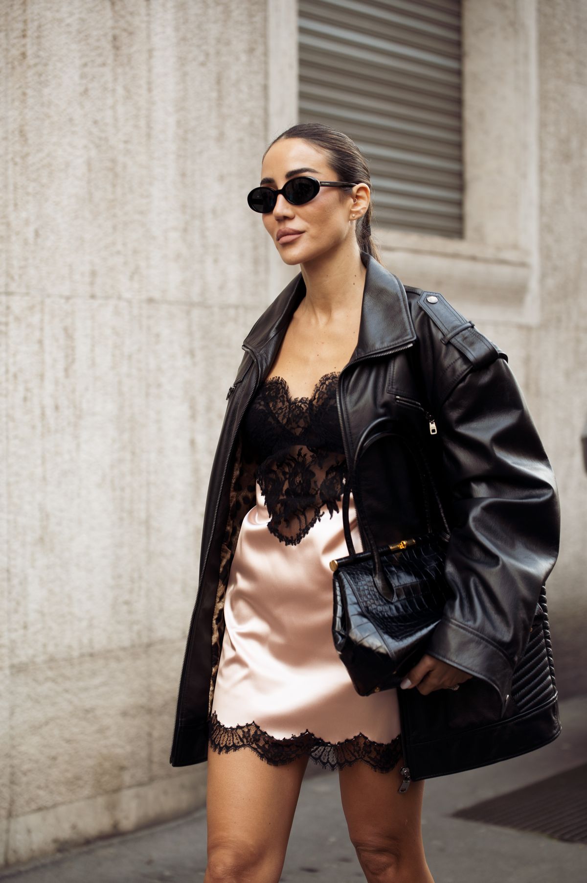 MILAN, ITALY - MARCH 01: Tamara Kalinic wears black leather jacket, black bag, peach or pale orange silk mini slip dress with black lace and sunglasses outside the Dolce & Gabbana fashion show during the Milan Fashion Week Womenswear Fall/Winter 2025/2026 on March 01, 2025 in Milan, Italy. (Photo by Raimonda Kulikauskiene/Getty Images)