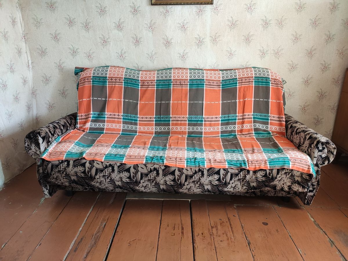 Rustic interiors. Photo of a village house. An old sofa covered with a blanket. Outback. Floral wallpaper. Russian interiors. The life of ordinary people. Village house interior. poor house