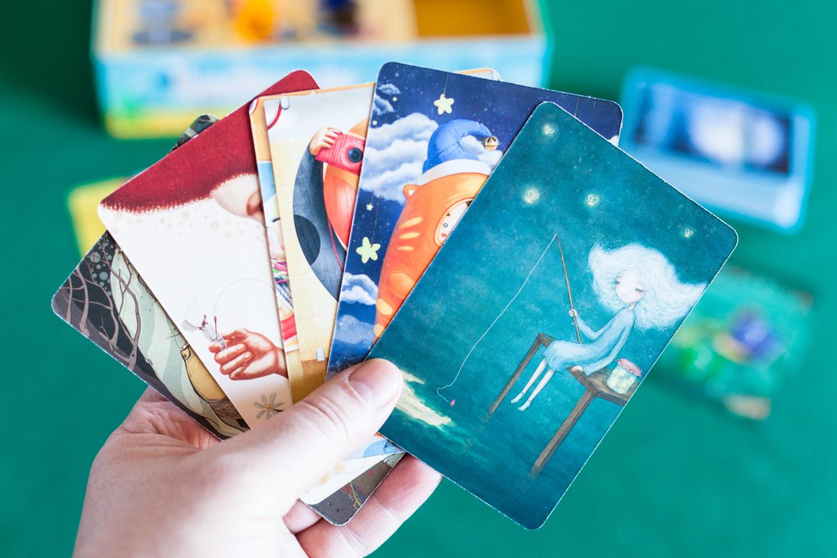 MOSCOW, RUSSIA - APRIL 3, 2019: player holds picture cards in Imaginarium game. Imaginarium is card game for stories and associations, russian variant of Dixit game