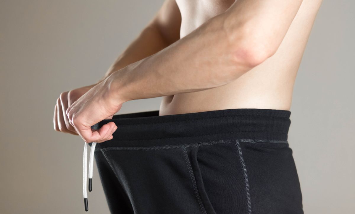 The man looks down his pants. Close up. Isolated on grey background.