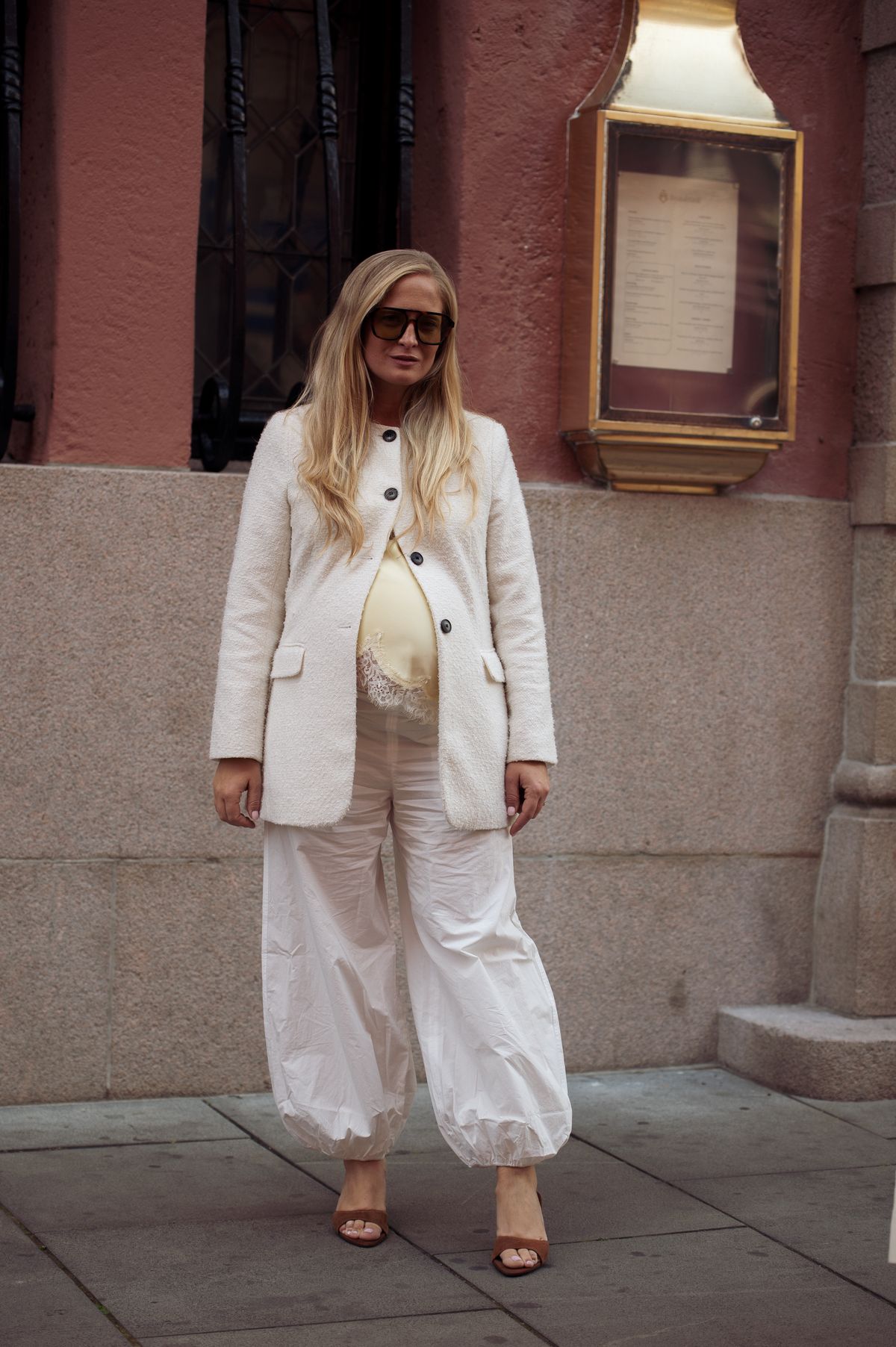 OSLO, NORWAY - AUGUST 26: Nathalie Helgerund wears white balloon pants, butter yellow silk top with lace and white blazer outside the Christian Aks show during Oslo Fashion Week on August 26, 2025 in Oslo, Norway. (Photo by Raimonda Kulikauskiene/Getty Images)