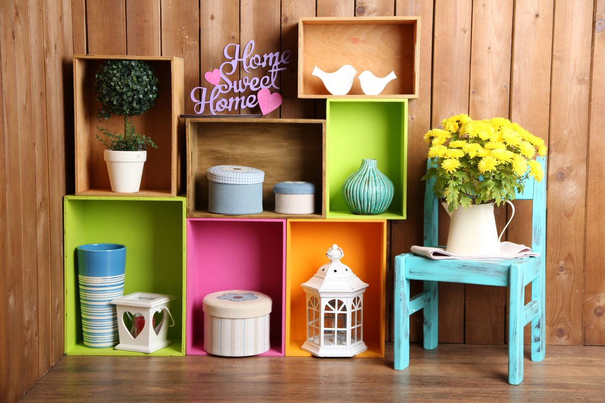 Beautiful colorful shelves with different home related objects on wooden wall background