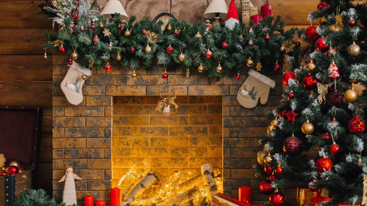 Christmas tree near the fireplace decorated with red and gold balls and toys in a wooden house