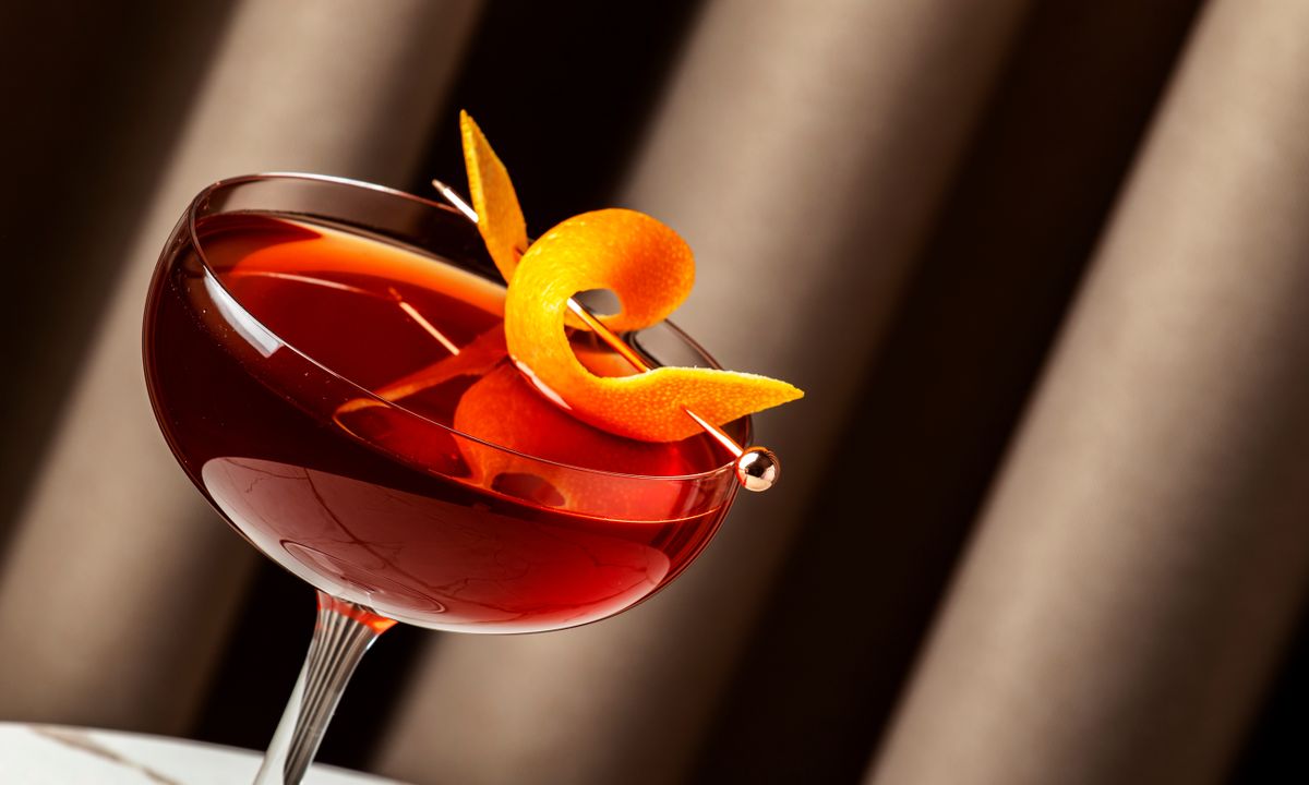 Crafting a vibrant revolver cocktail with bourbon and orange bitters in a stylish setting