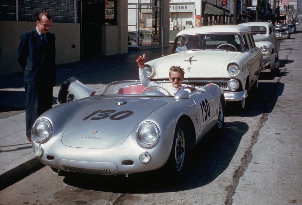Actor James Dean gives a thumbs-up sign from his Porsche 550 Spyder, the Little Bastard, while parked on Vine Street in Hollywood. Dean, who had taken up racing the year before, owned the car only nine days when he lost his life in a fatal highway accident while driving the Porsche to a Salinas race.
