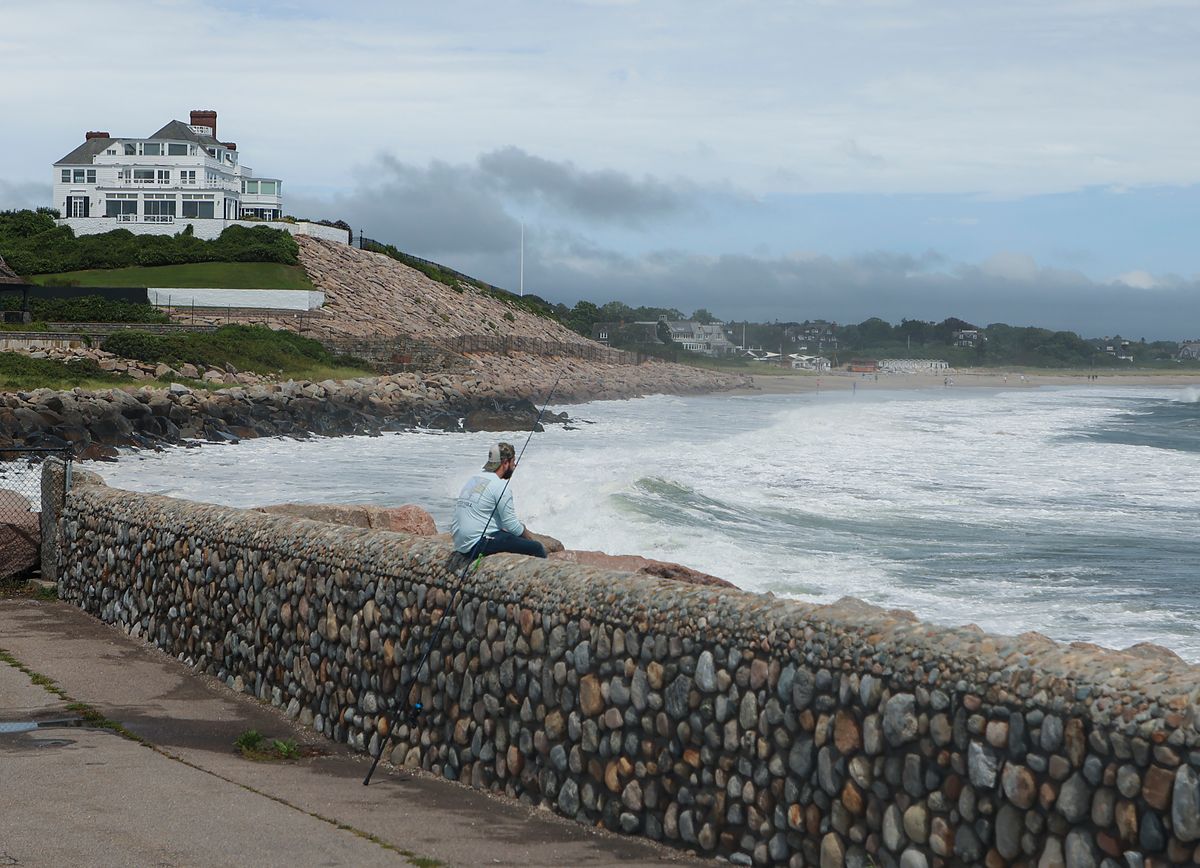 Westerly, RI - August 22: A man fishes at the Watch Hill Lighthouse for stripped bass with home of Taylor Swift in the background during the eye of the Tropical Storm Henri in Westerly, RI on Aug. 22, 2021. (Photo by Matthew J. Lee/The Boston Globe via Getty Images)