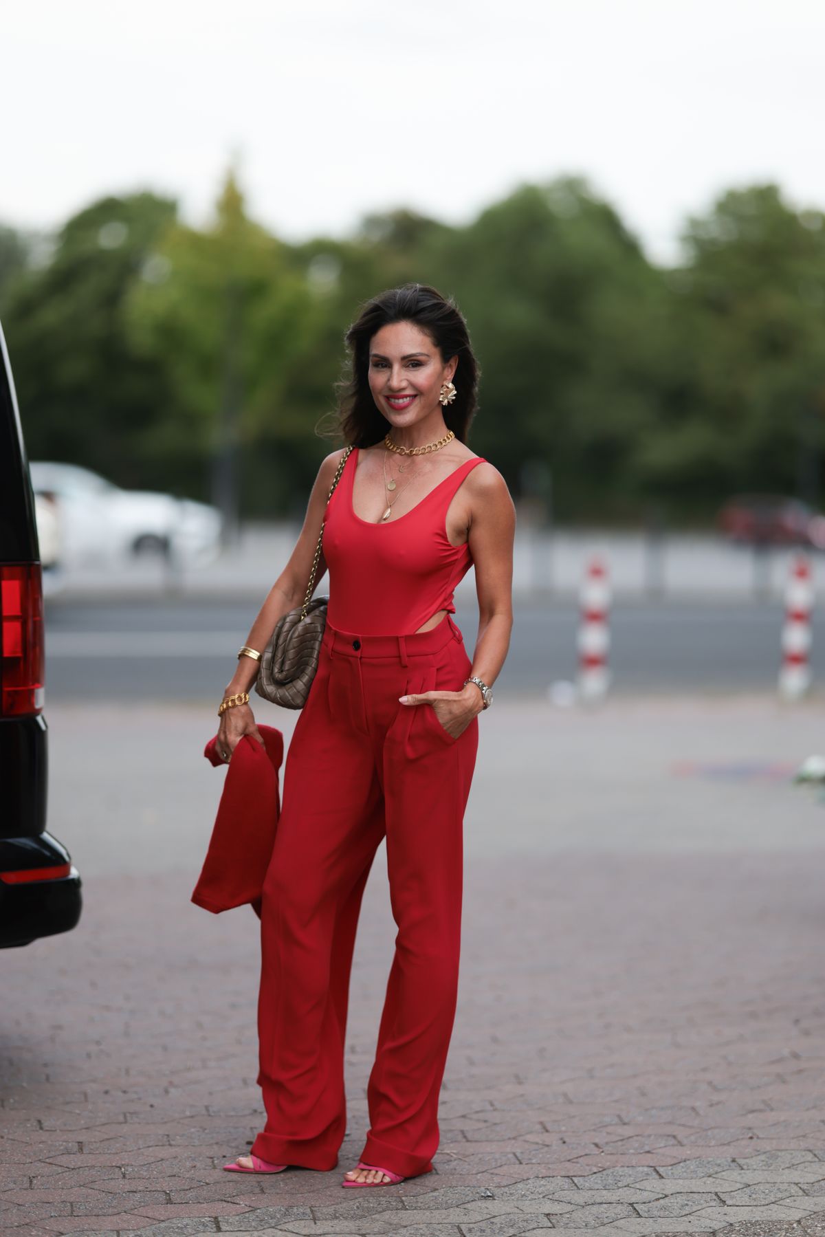 DUESSELDORF, GERMANY - JULY 19: Nazan Eckes is seen a red bodysuit, wide-leg red pleated pants, a beige leather bag, and pointed pink heeled sandals, while holding a red knit cardigan, during the RIANI CRUISE 4.0. Dreamland at RSR Steiger Düsseldorf 1 on July 19, 2025 in Duesseldorf, Germany. (Photo by Jeremy Moeller/Getty Images for RIANI)