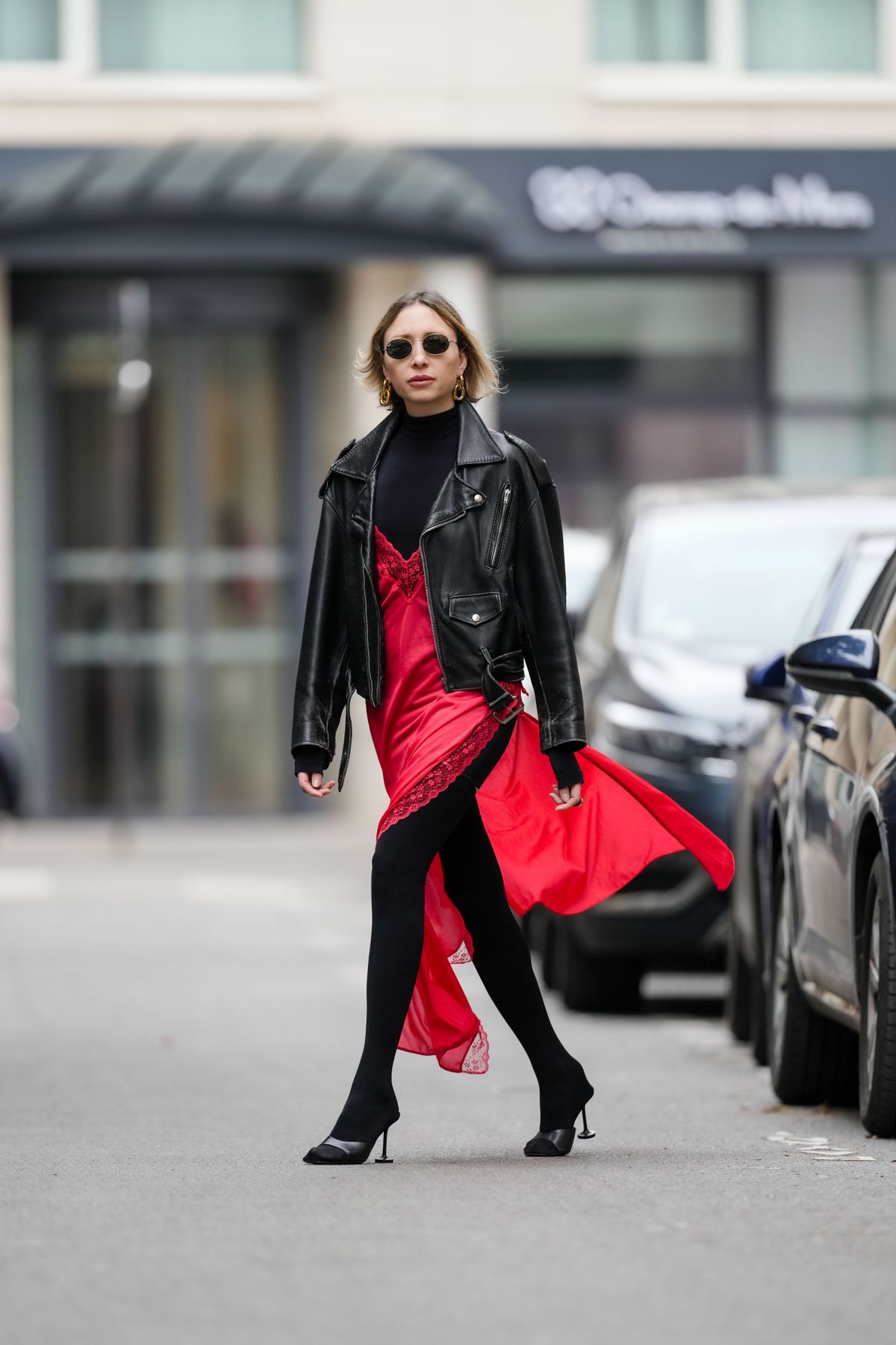 PARIS, FRANCE - MAY 08: Emy Venturini wears Ray Ban sunglasses, golden earrings / jewelry, a red low-neck long lustrous dress with floral embroidered neckline, a black turtleneck top from Intimissimi, a black leather biker jacket, black tights, black high heels leather shoes from Balenciaga, during a street style fashion photo session, on May 08, 2024 in Paris, France. (Photo by Edward Berthelot/Getty Images)