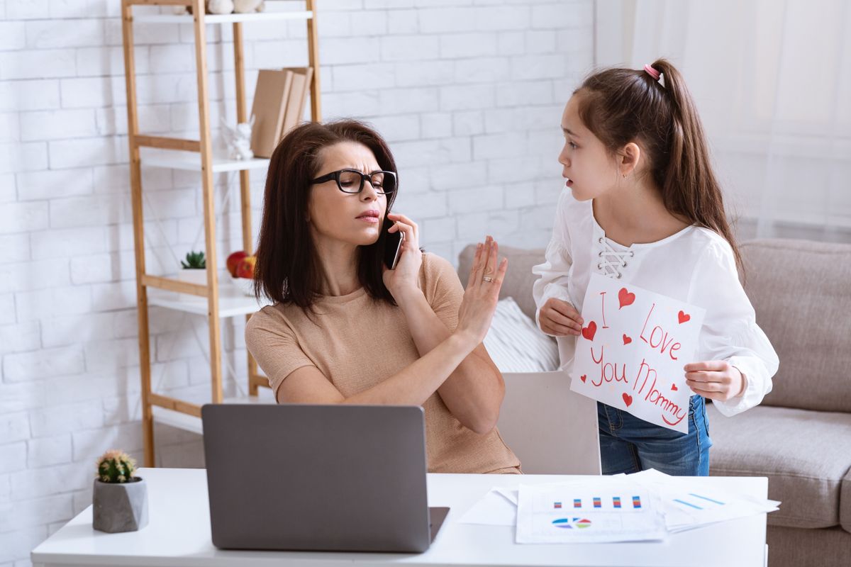 A távolságtartó anya nem feltétlenül kegyetlen – sokszor maga is egy szeretet nélküli közeg gyermeke. Remote job and parenting concept. Busy mother neglecting her daughter while working with laptop and phone at home