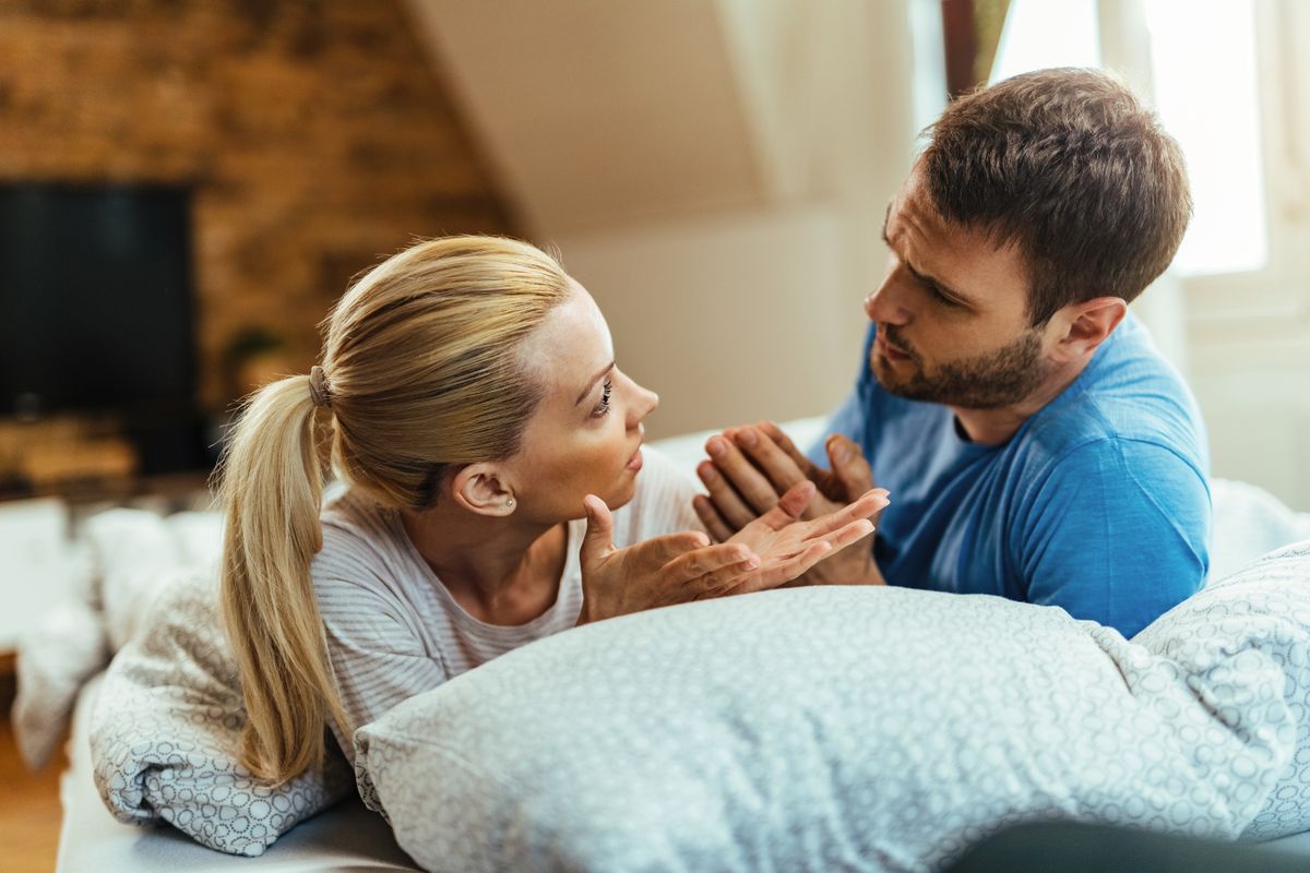 Young couple talking while having relationship problems in bedroom.