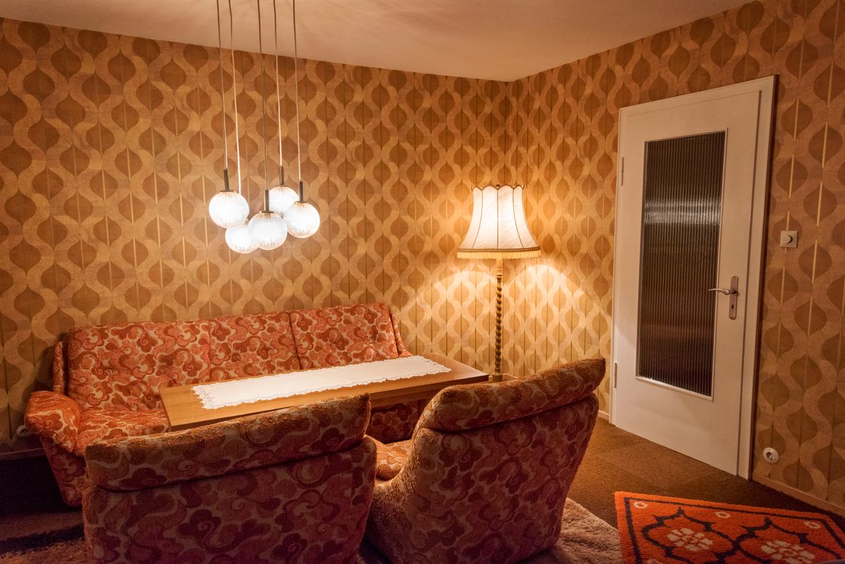 Egy régi lakberendezési tárgyakkal berendezett nappali kanapéval, szőnyeggel és lámpákkal.