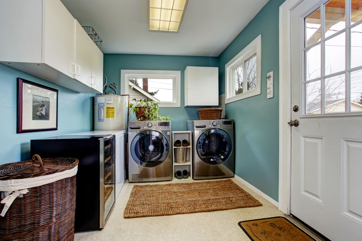 Light blue laundry room with modern steel appliances and white cabinets