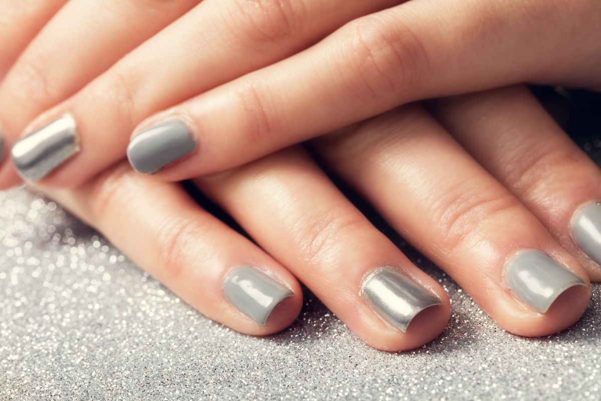 Woman's nails with shiny silver hybrid manicure. Close-up