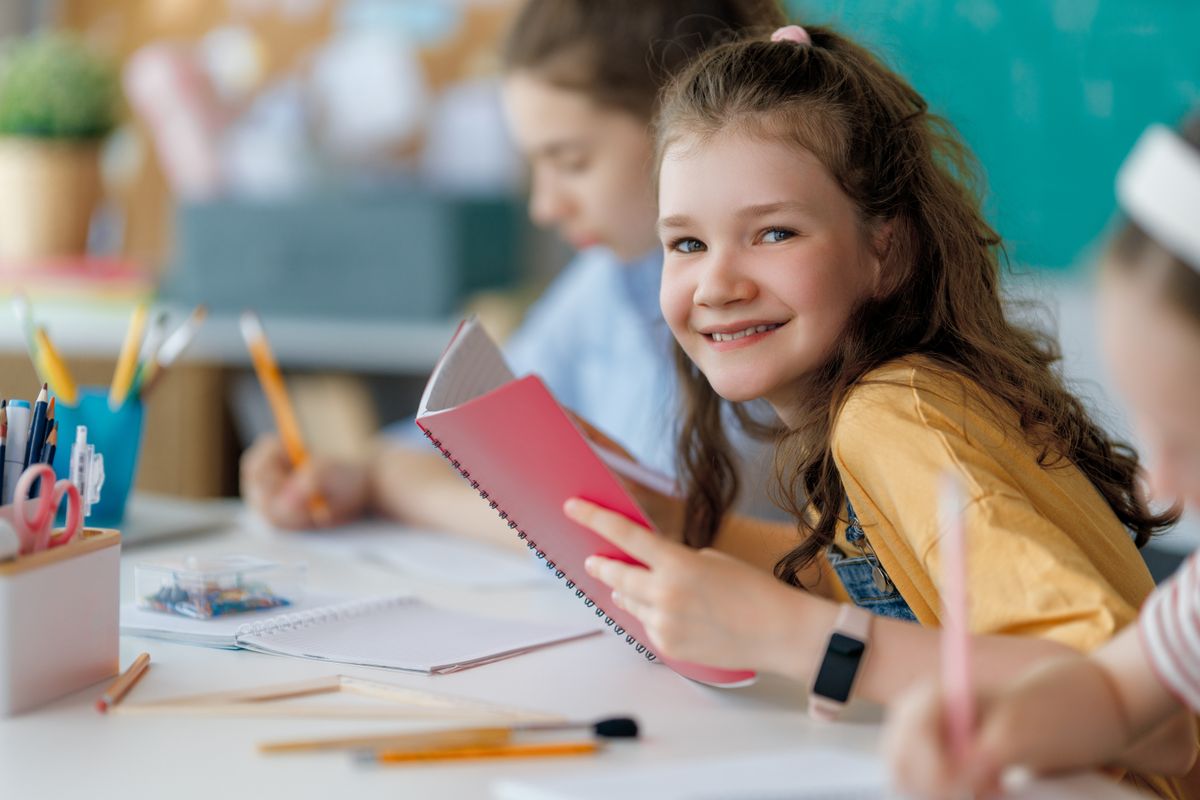 Kislány mosolyog társai körében, mert a tanulását nem a piros hibák határozzák meg. nem 