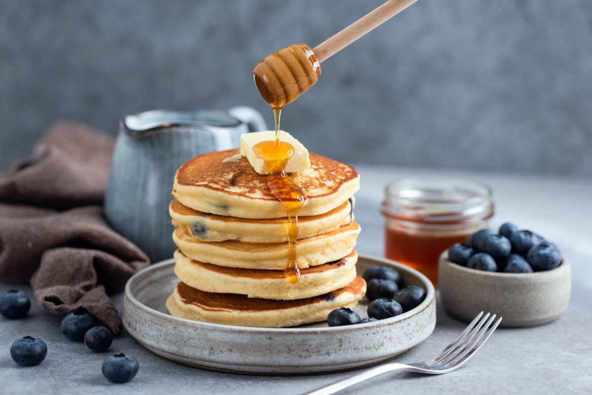 Vastag, puha amerikai palacsinta kerül a tányérra, amit bőséges juharsziruppal tálalnak.