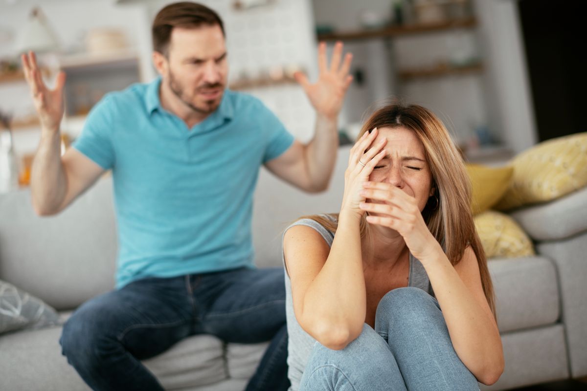 Bántalmazó kapcsolat – egy férfi üvölt feleségével, aki nem bírja, arcát a kezeibe temeti fájdalmában.