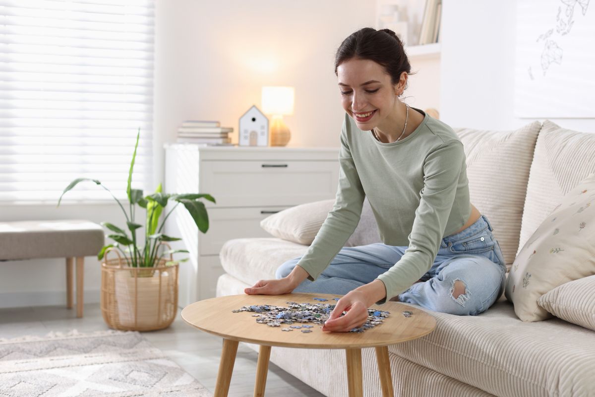 A logikai kvíz kérdések olyanok, mint a puzzle, amit a képen szereplő lán rak i a dohányzóasztalon.