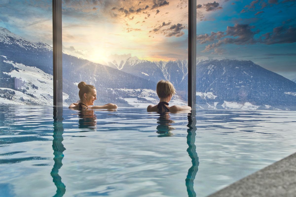 Women enjoying the panoramic view from the pool in the alps