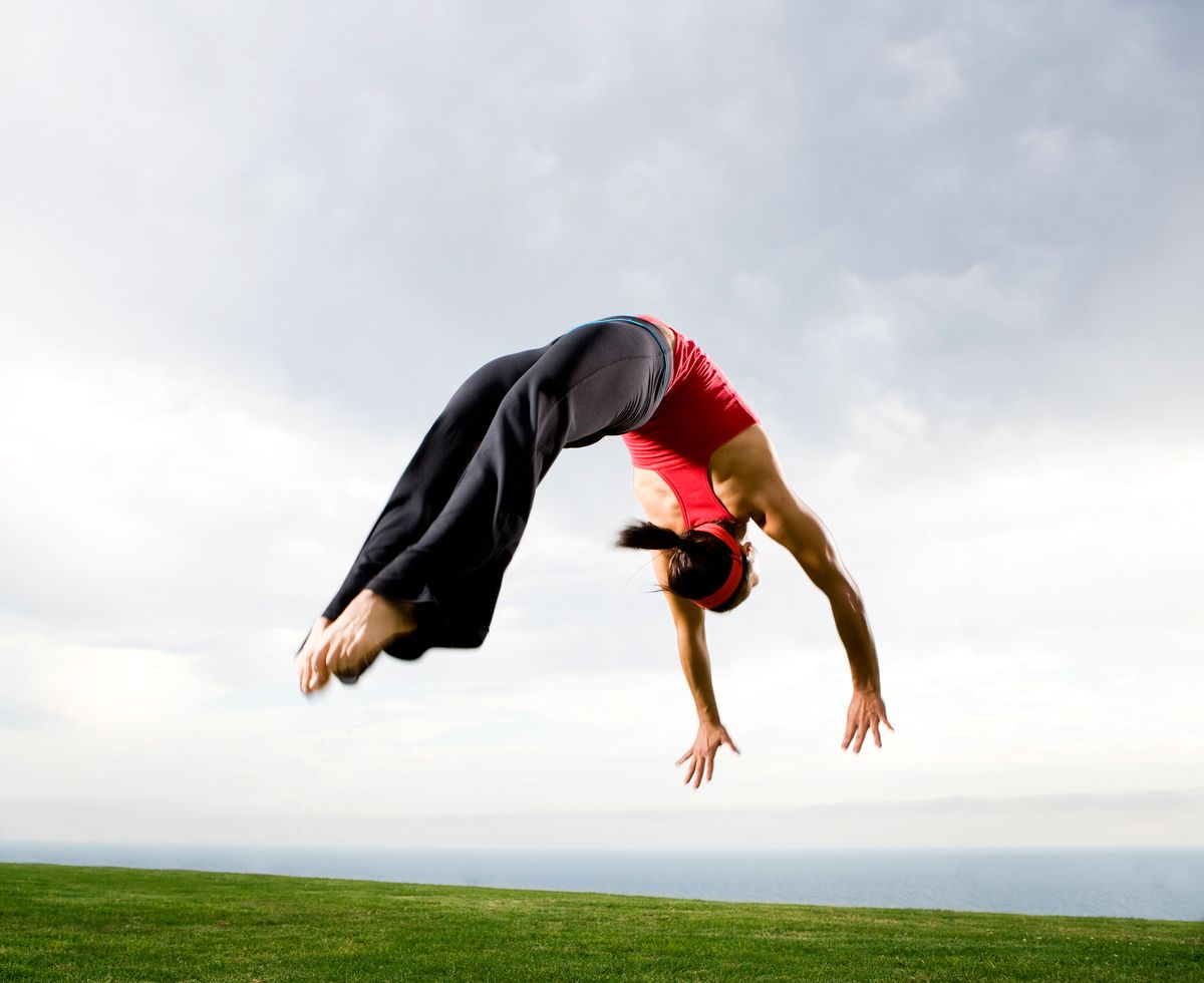 Egy női sportok, torna, egy nő szaltó közben. 