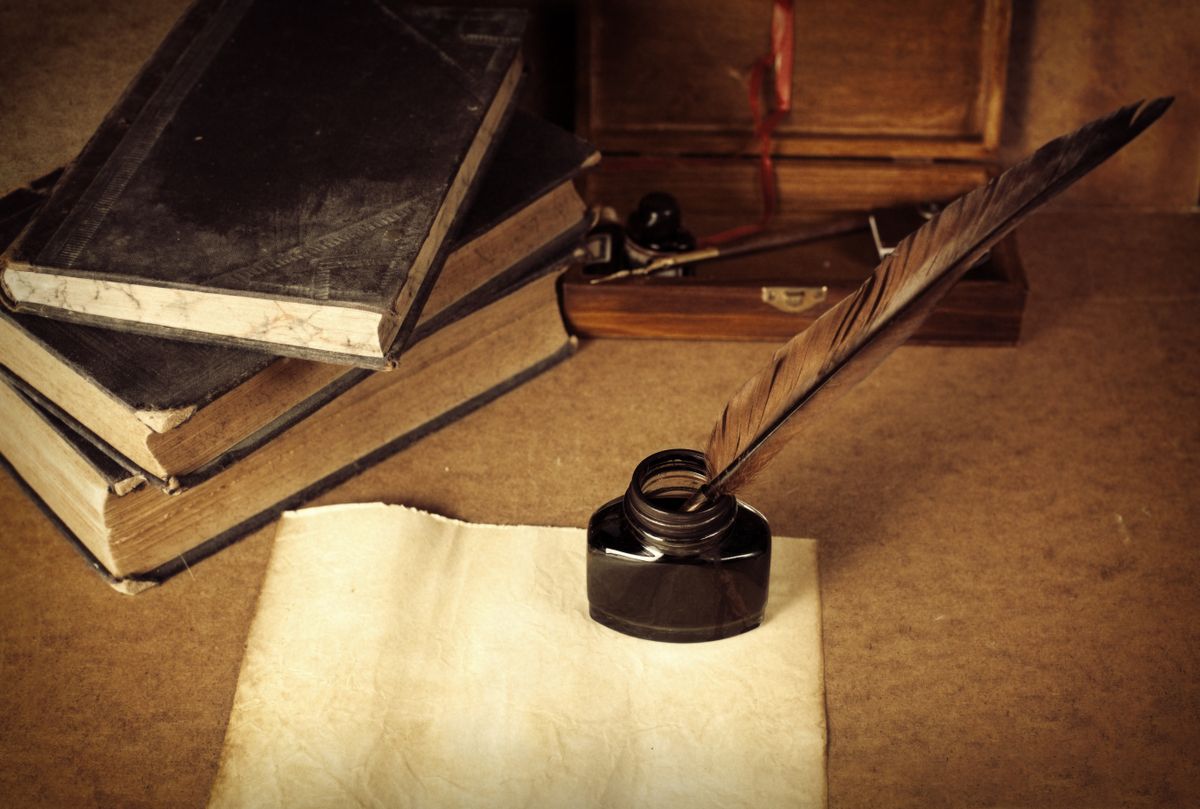 Történelemkvíz: régi könyvek és toll, amivel írnak egy papírra. 