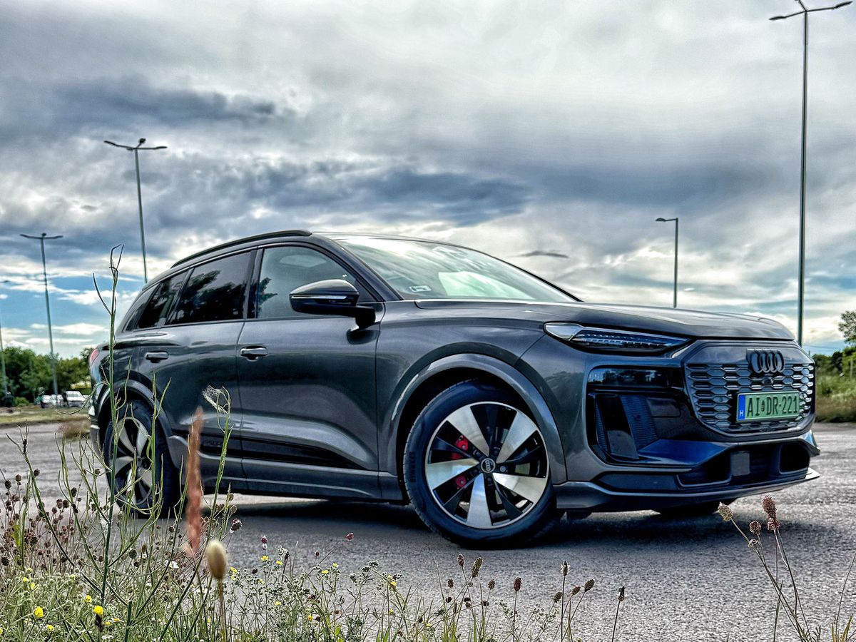 Audi Q6 modell oldalról fotózva egy parkolóban. 