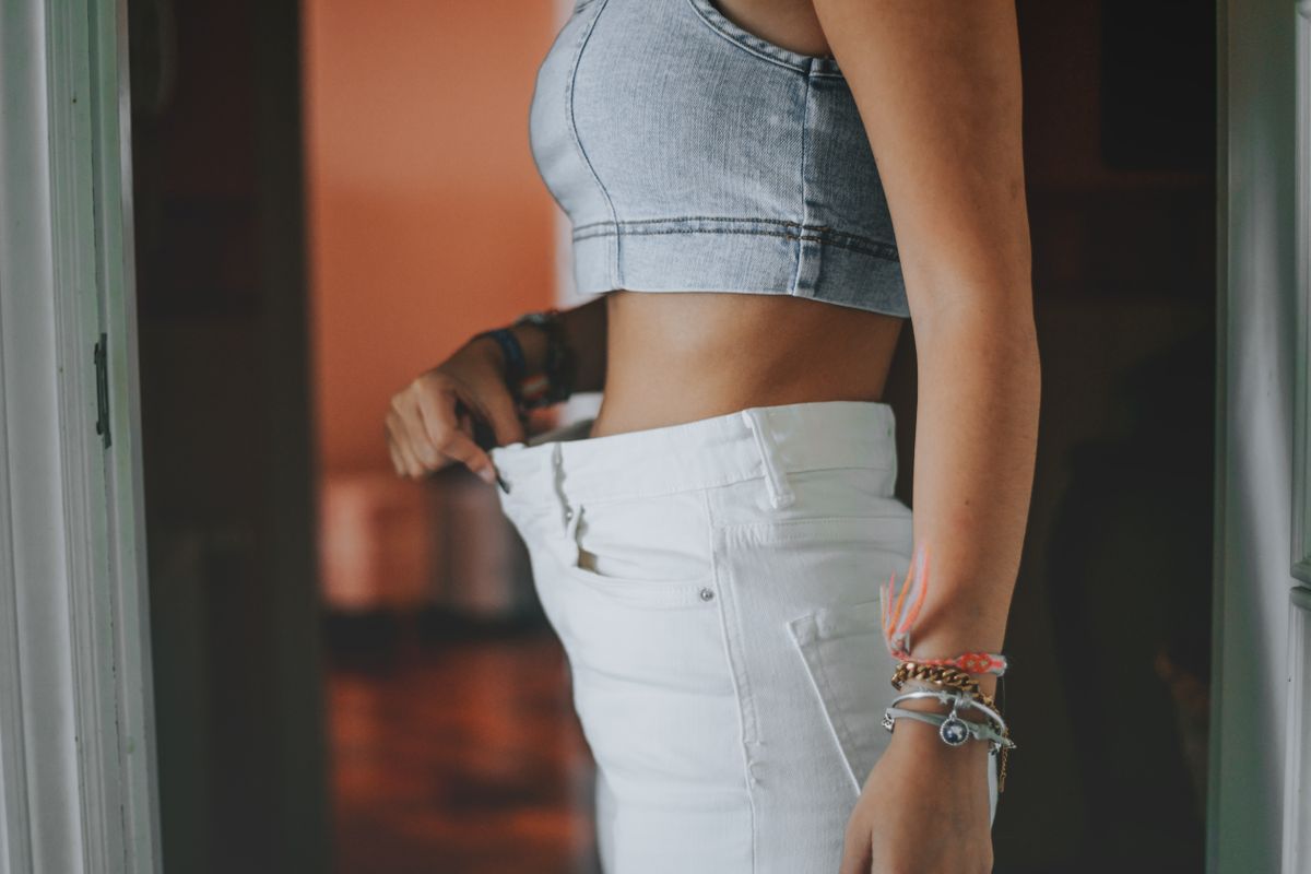 Egy nő a fogyókúra hatására leadott néhány kilót, ezért túl bő a nadrágja. 