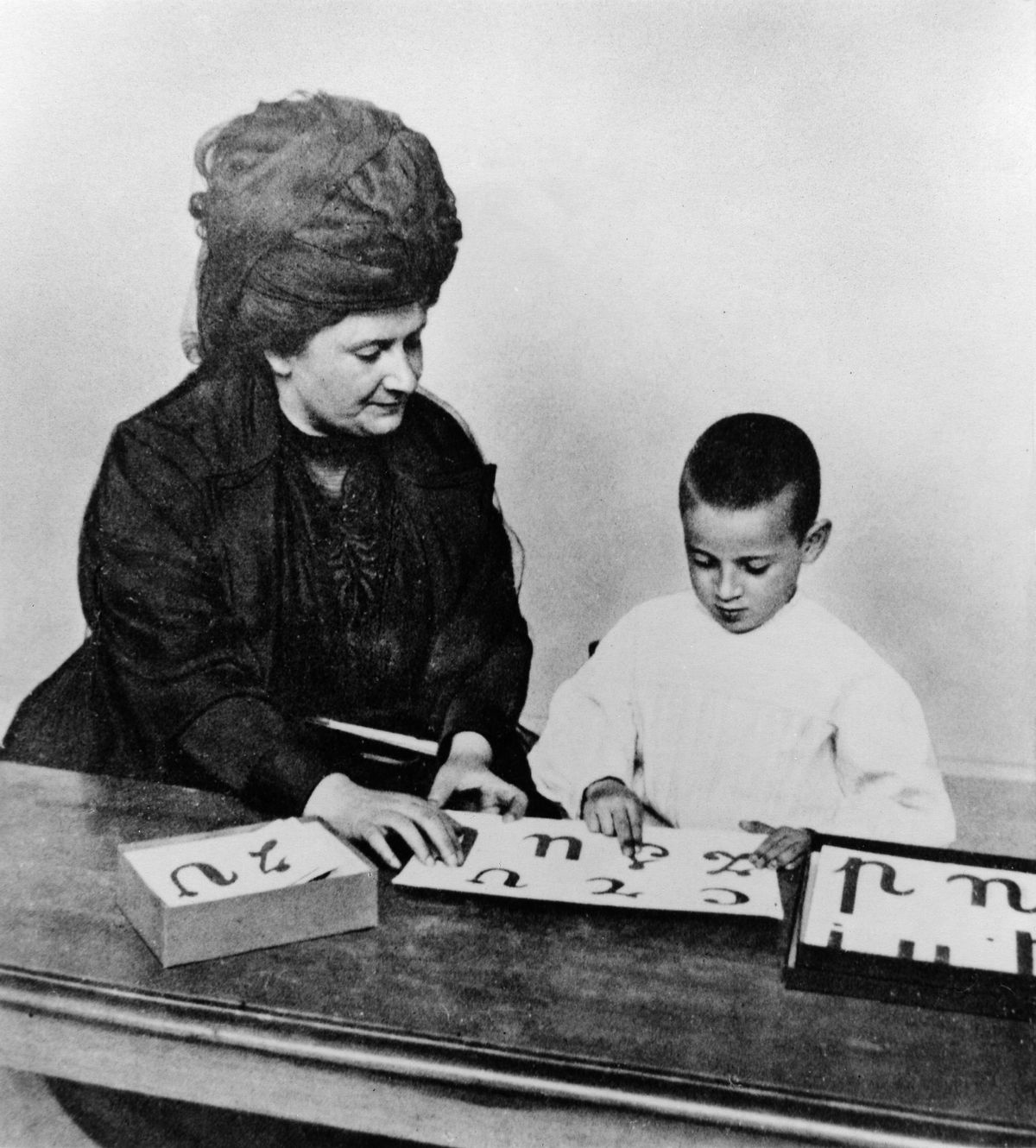 Maria Montessori egy gyerekkel játszik. 