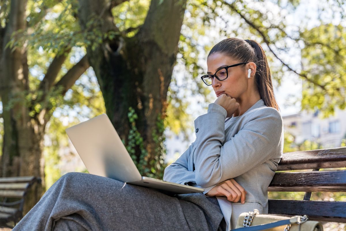 Fiatal nő a parkban egy képes rejtvényen gondolkodik 