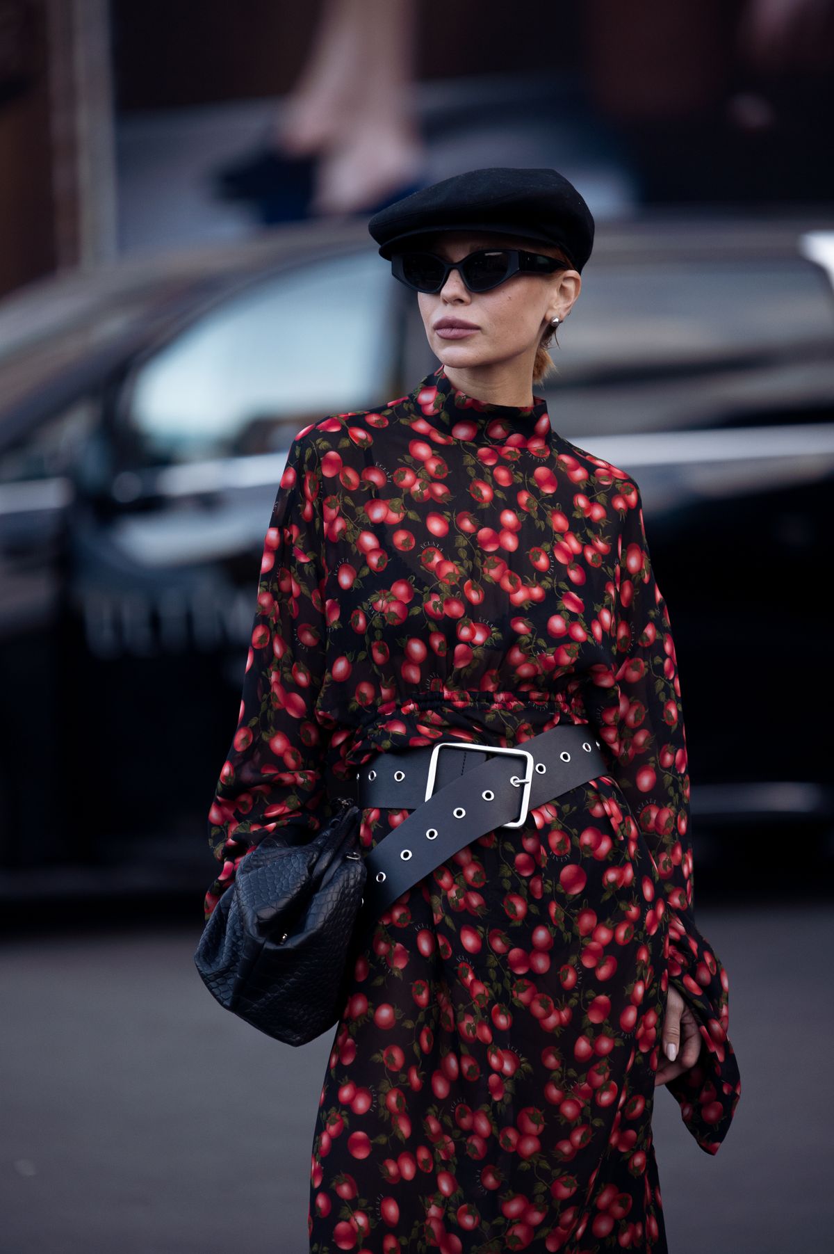 YEREVAN, ARMENIA - OCTOBER 24: Lina Dembikova wears a black sheer dress printed with red tomatoes, cinched at the waist with a wide black belt, paired black sunglasses, a black beret, and a textured black bag during Yerevan Fashion Week on October 24, 2025 in Yerevan, Armenia. (Photo by Raimonda Kulikauskiene/Getty Images)