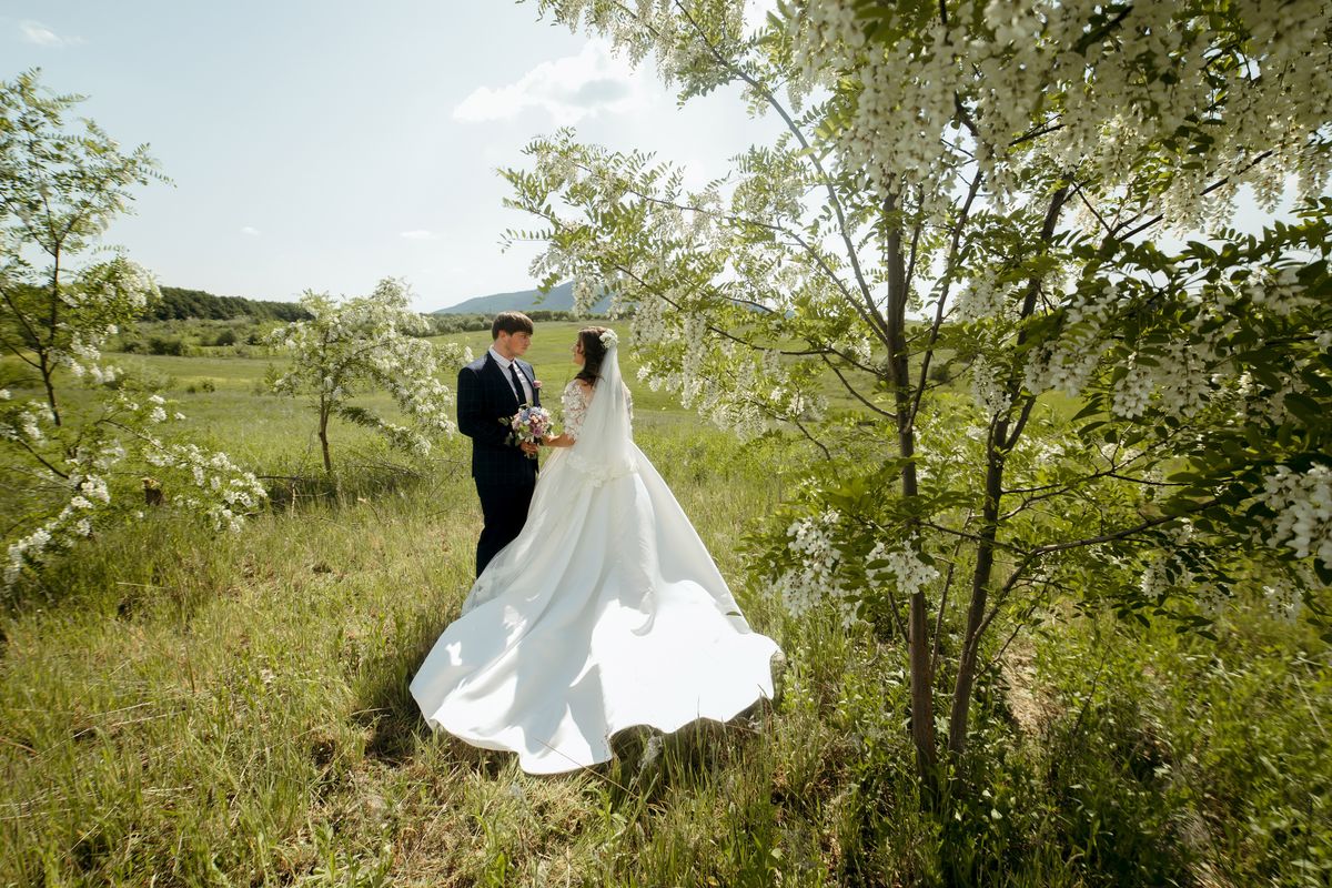 menyasszony és vőlegény egy réten sétál