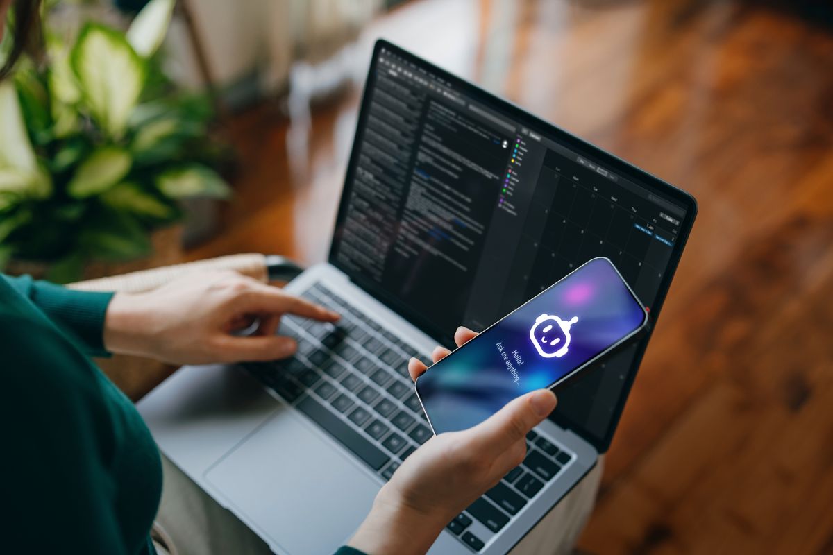 AI chatbot, ChatGPT munka közben egy telefonon és laptopon.