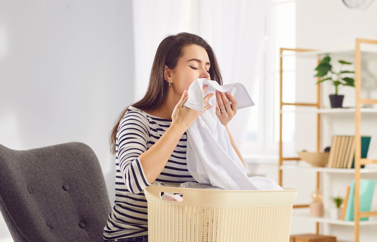 Fiatal nő a mosott ruha friss illatát szagolja
