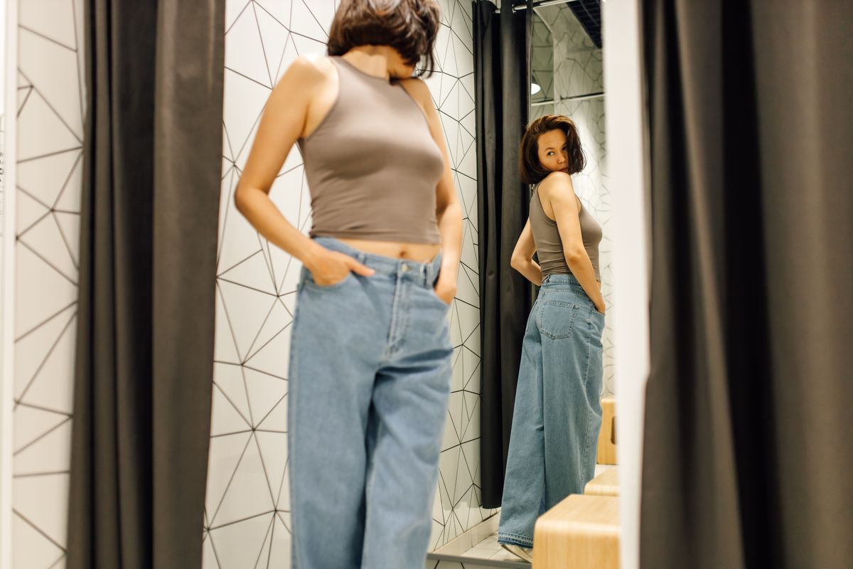 Egy nő azt nézi magán egy tükörben, hogy megfelelő-e a fenék formája.