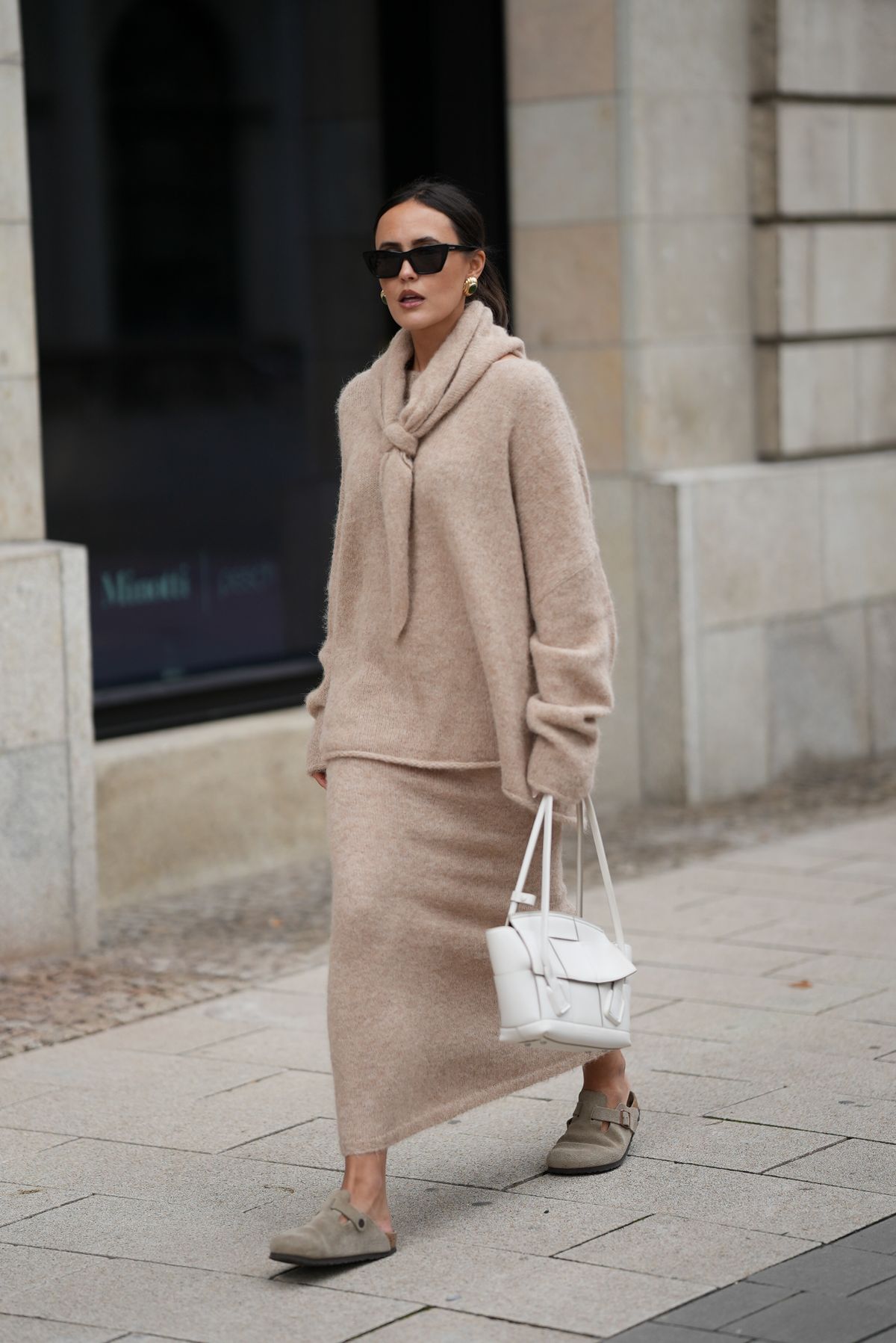 HAMBURG, GERMANY - OCTOBER 16: Laura Noltemeyer is seen wearing an oversized beige alpaca wool sweater with tie-back detailing by Aylin König; a long alpaca wool knit skirt in a straight cut by Aylin König; an alpaca knit scarf draped and knotted around the neck by Aylin König; beige suede Boston clogs by Birkenstock; a white intrecciato leather handbag called „Arco Bag“ by Bottega Veneta; slim black cat-eye sunglasses by Yves Saint Laurent; gold statement earrings with a green stone detail by Mango; her brown and straight hair is tied in a low ponytail on October 16, 2025 in Hamburg, Germany. (Photo by Moritz Scholz/Getty Images)