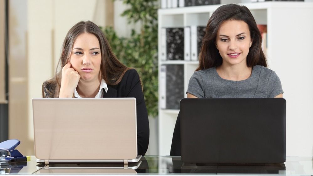 Irigység a munkában két nő között, laptop előtt ülve