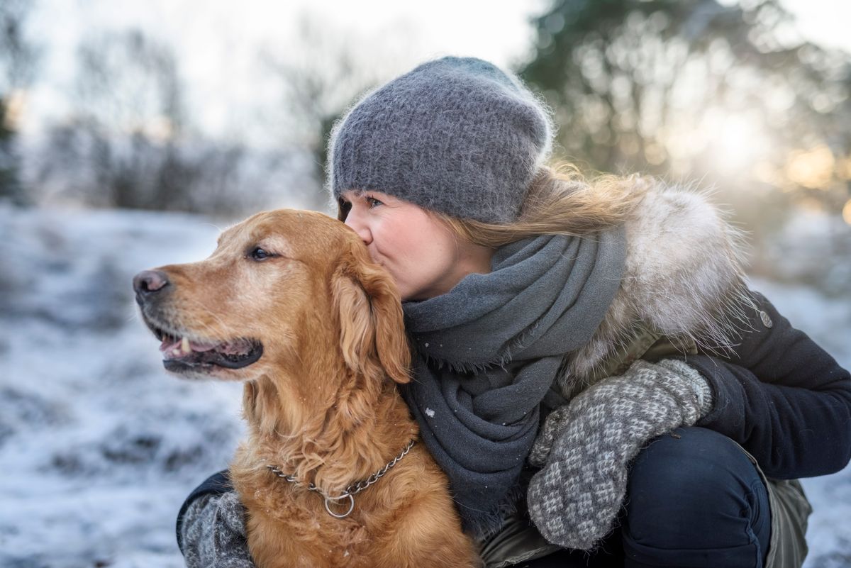 A képen csinos fiatal nő öleli a kutyáját a havas mezőn. A háziállatok elvesztését nehéz feldolgozni. 