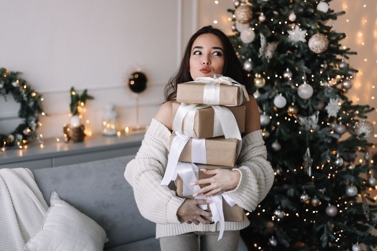 Karácsonyi ajándékokat tart a kezében egy nő.