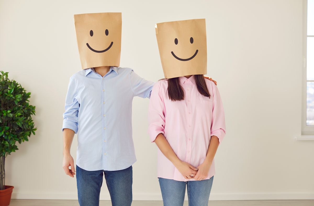 érzelmek elhallgatása: fiatal pár a fején papírtasakkal, amire mosolyt rajzoltak