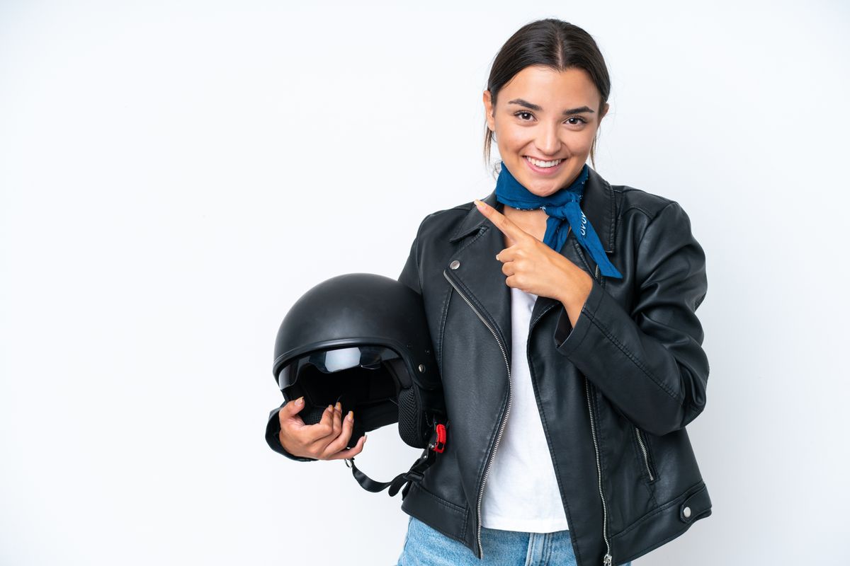 Young caucasian woman with a motorcycle helmet isolated on blue background pointing to the side to present a product