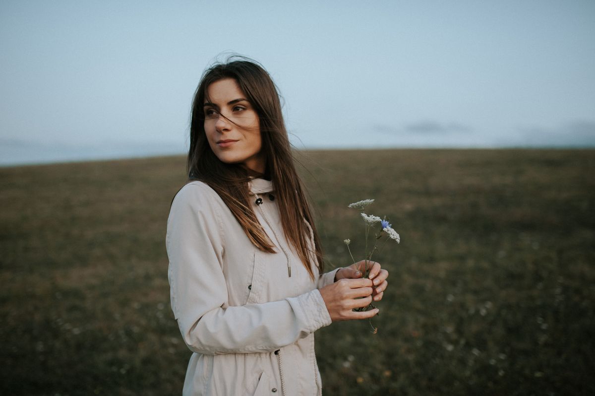 mezőn álló nő, kabátban