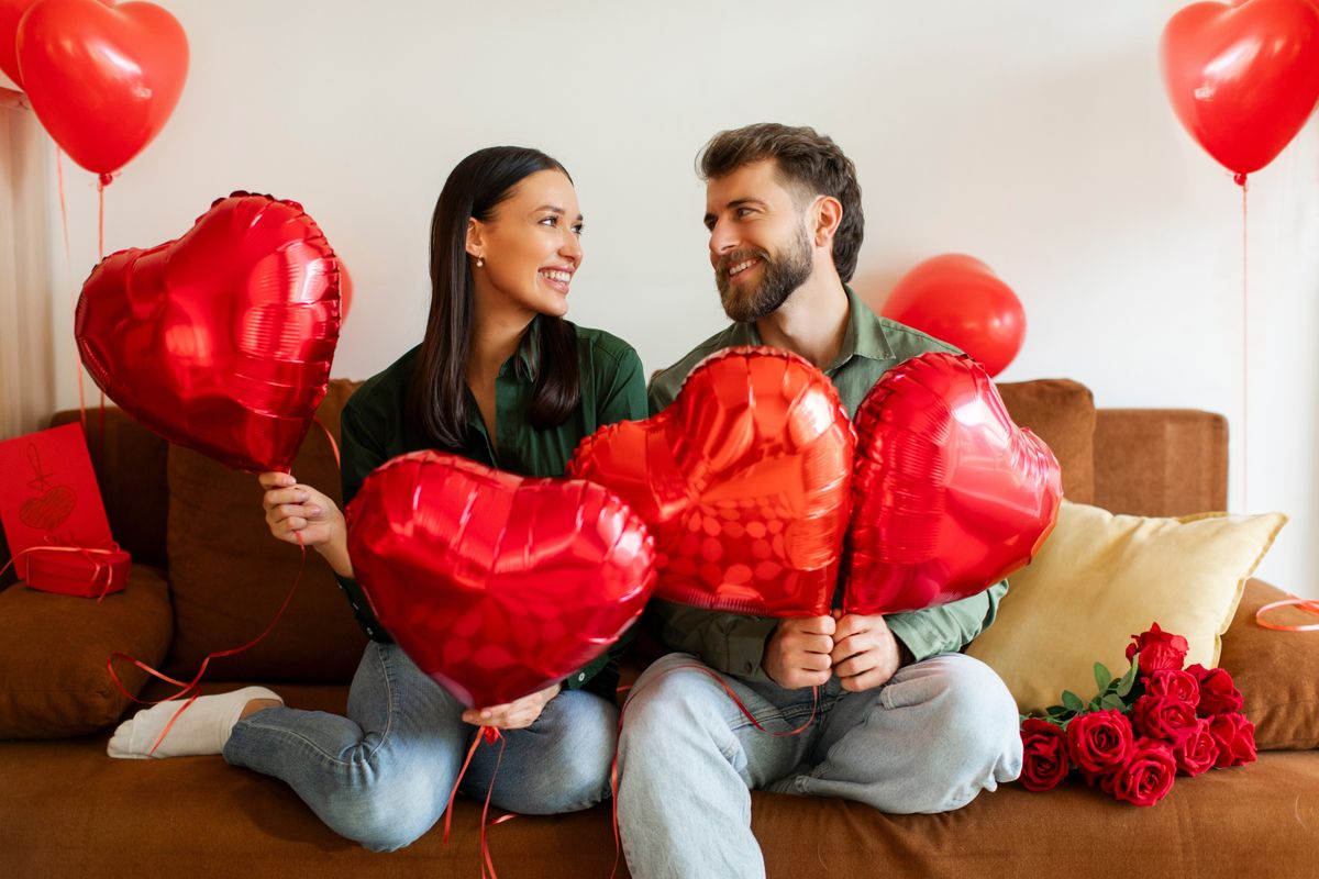 Valentin-napon a fiatal pár lufikkal a kezükben ül a kanapén.