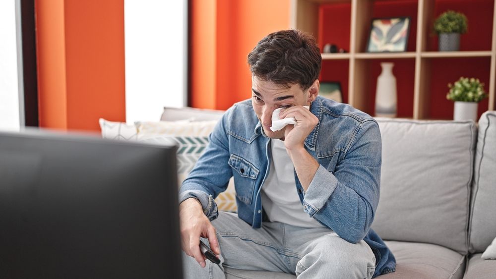 Fiatal férfi nem fojtja vissza a sírást film közben. 