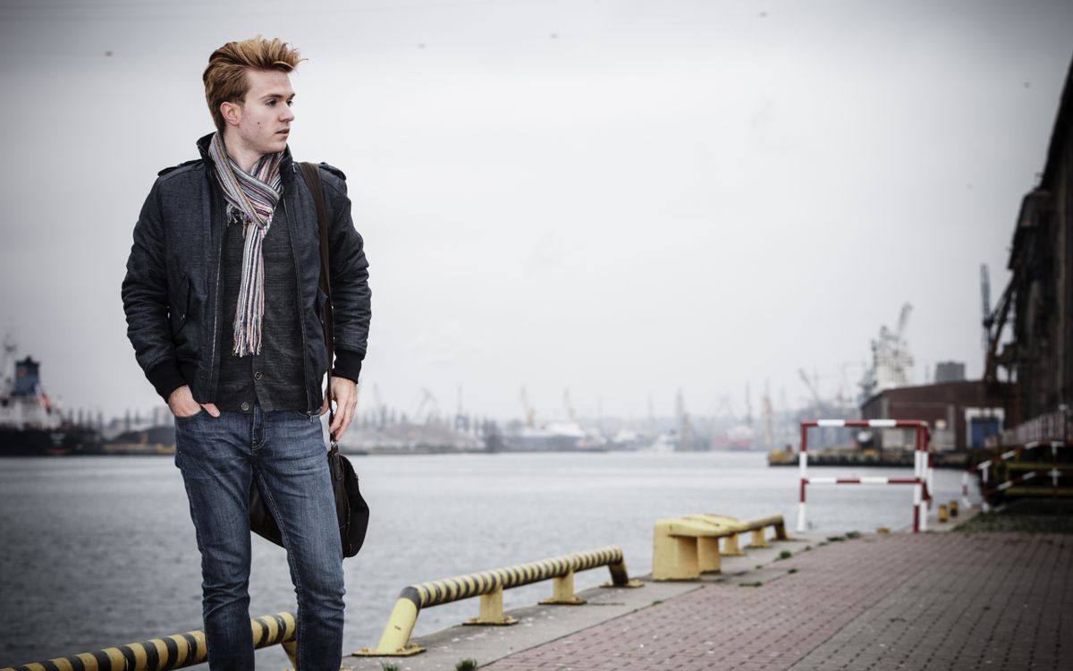 Young handsome man fashion model casual style with bag on street urban industrial background