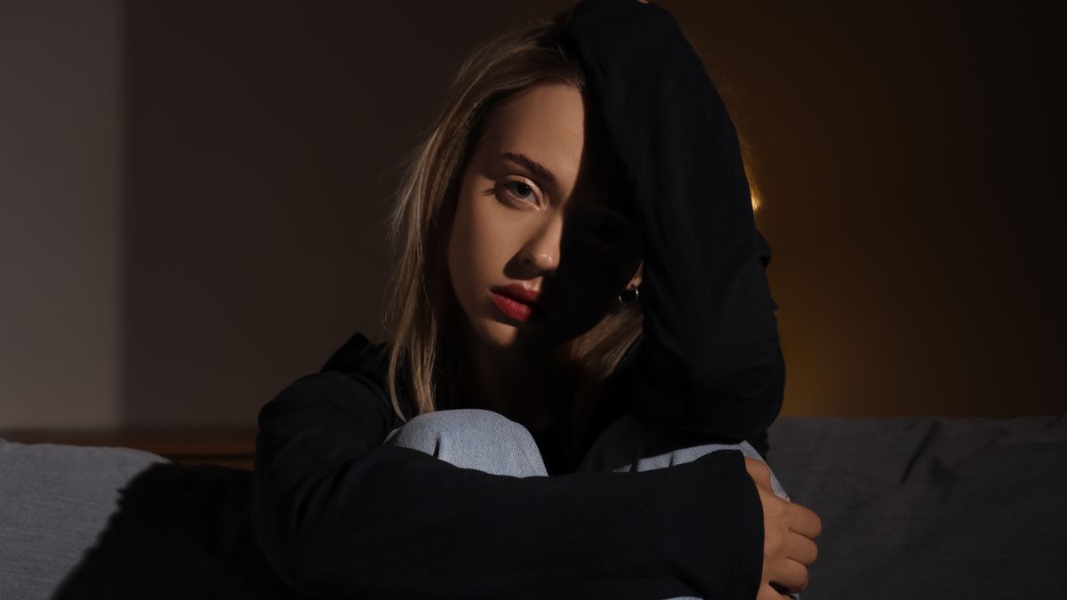 Korai vetélésen átesett, szomorú nő a kanapén.