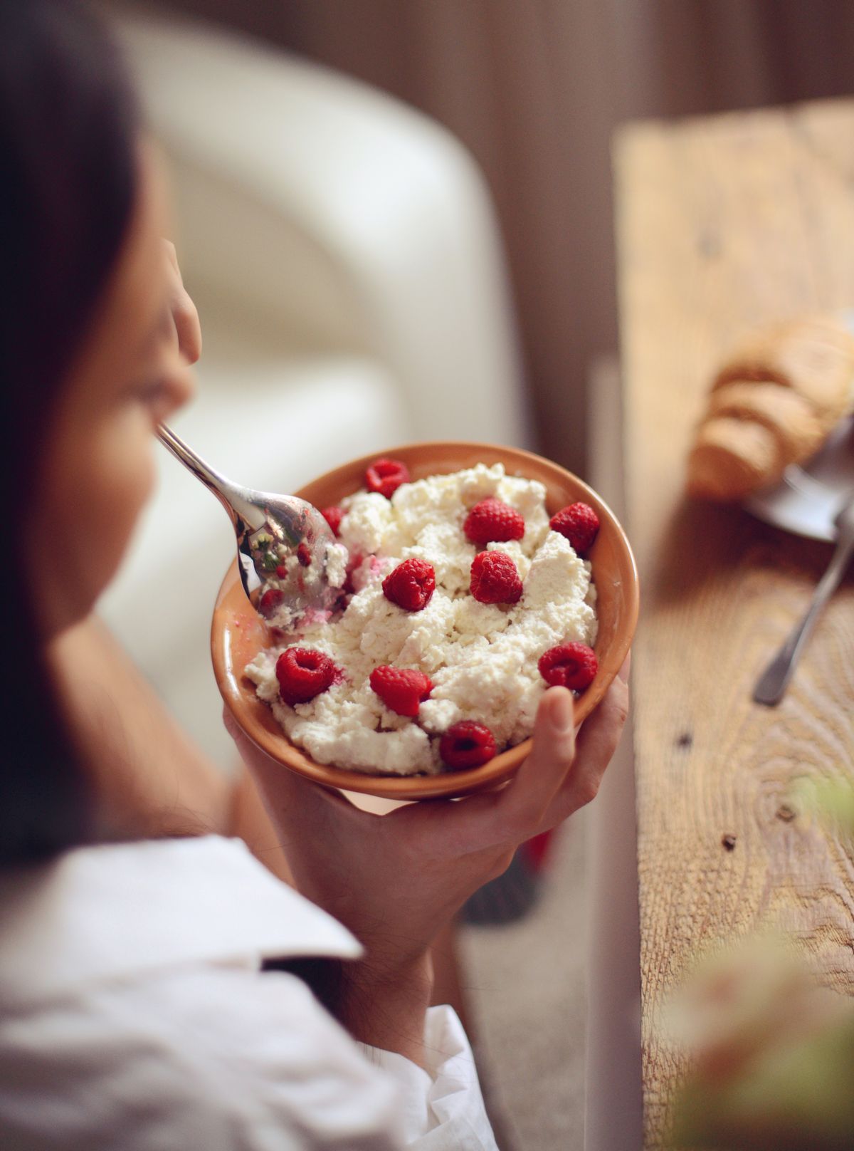 Szuperétel, cottage chees-t eszik egy nő reggelire málnával. 