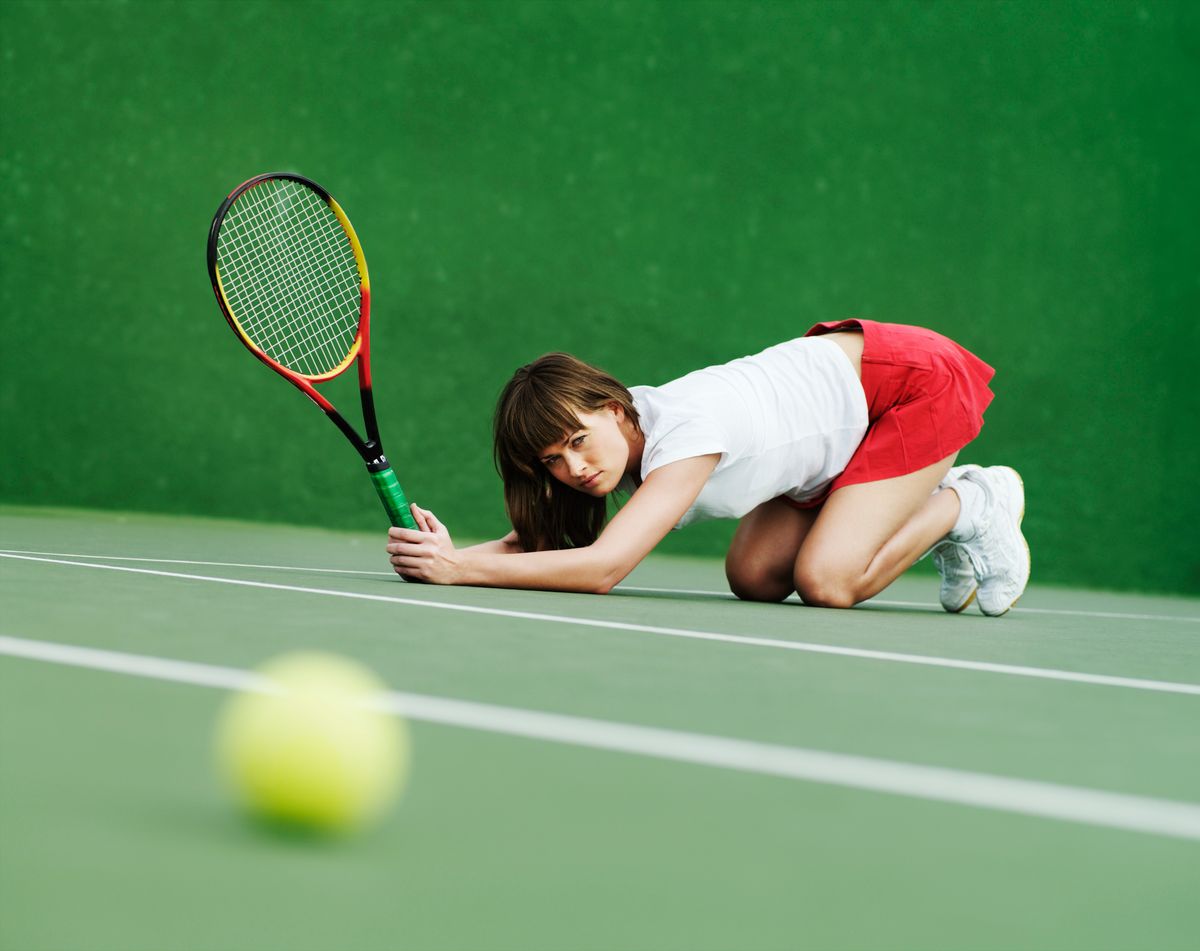 Egy amatőr női teniszező néz egy teniszlabdát a földön.