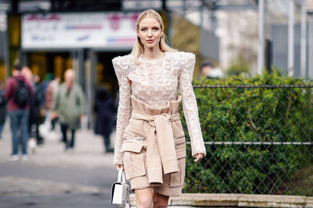 PARIS, FRANCE - MARCH 01: Leonie Hanne wears a geometrical pattern embroidered shoulder pad lace top, shorts featuring an attached pullover, a white Balmain bag, high boots, outside Balmain, during Paris Fashion Week Womenswear Fall/Winter 2019/2020, on March 01, 2019 in Paris, France. (Photo by Edward Berthelot/Getty Images)