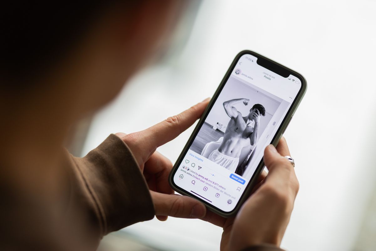 Instagram-jelek: egy nő kezében egy telefonon egy feszítő, izmos férfi. 