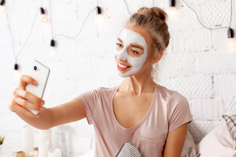 Fiatal lány téli arcmaszkban szelfizik.