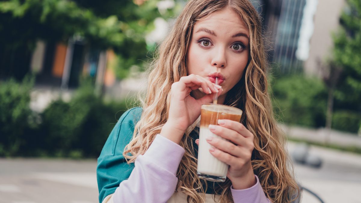 Tejfehérje-allergia tüneteit nem mutató nő issza a tejet az utcán.